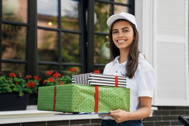 Deliverywoman holding gift boxes and folder