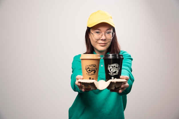 Free photo deliverywoman offering cardboard of coffee cups on a white. high quality photo