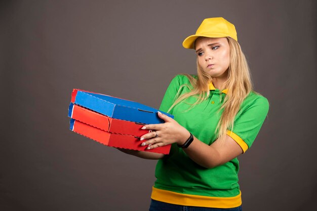 Deliverywoman in uniform holding cardboards of pizza . High quality photo