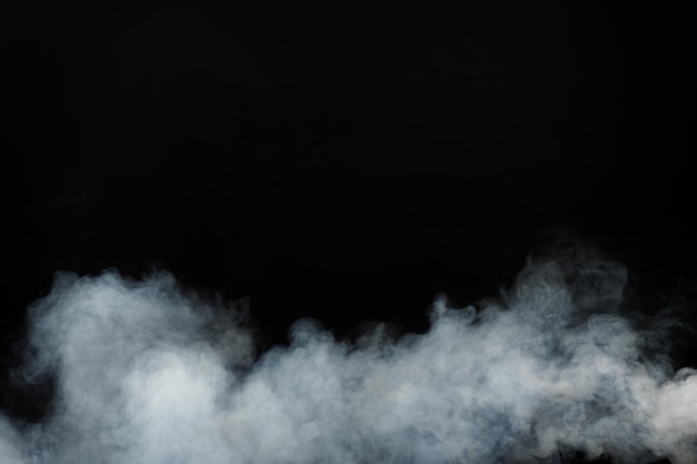 Плотные пушистые клубы белого дыма и тумана на черном фоне, абстрактные облака дыма, размытое движение не в фокусе. дымящие удары от машинной мухи с сухим льдом и развевающиеся в воздухе, эффект текстуры