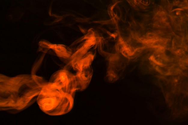暗い背景上の抽象的なオレンジ色の煙の密な煙