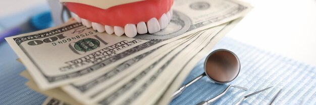Dental artificial jaw instrument and one hundred dollar bills on dentist desk dental treatment