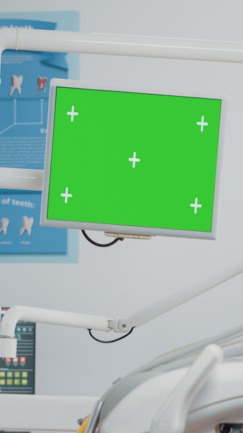 Team odontoiatrico che lavora con lo schermo verde sul computer nell'armadietto per l'igiene orale. dentista e assistente che parlano mentre guardano lo sfondo isolato e il modello di mockup per l'odontoiatria.
