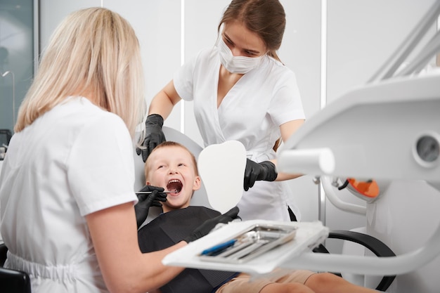 치과 사무실에서 아이 치아를 검사하는 치과 의사 및 조수