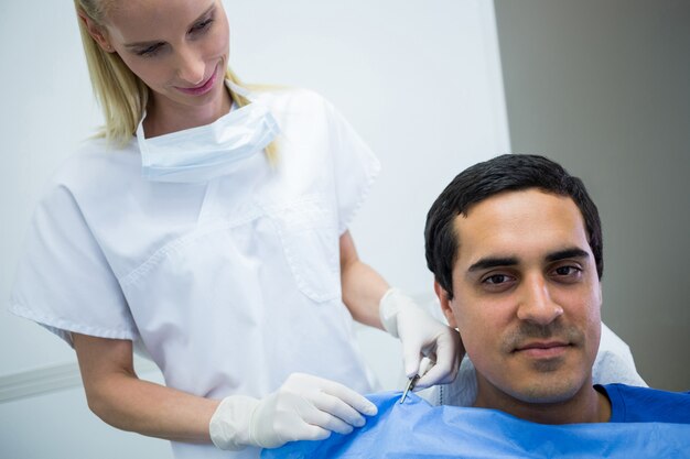 Dentist assisting a patient to wear dental apron