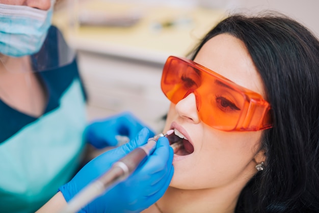 Foto gratuita dentista che cura i denti del paziente in occhiali