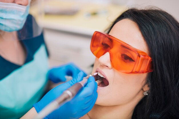 Стоматолог лечит зубы пациента в очках