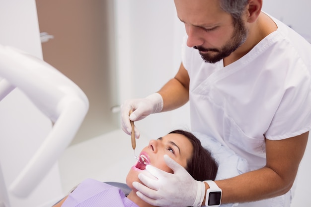 Dentist examining female patient teeth with a mouth mirror