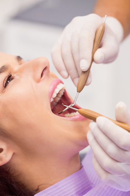 歯科医が女性患者の歯を調べる