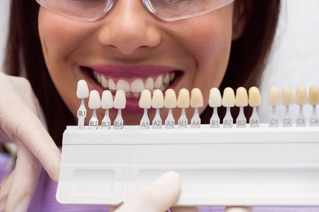 Dentista che esamina paziente femminile con le tonalità dei denti