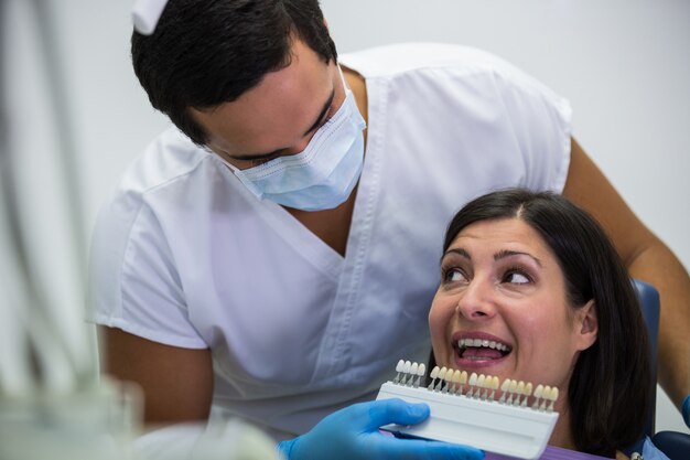 Dentist examining female patient with teeth shades