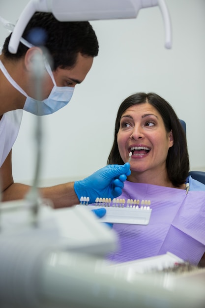 Dentist examining female patient with teeth shades