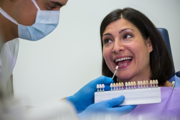 Dentist examining female patient with teeth shades