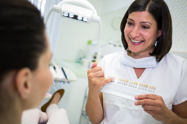 Dentist examining female patient with teeth shades