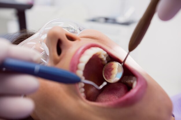 Dentist examining a female patient with tools