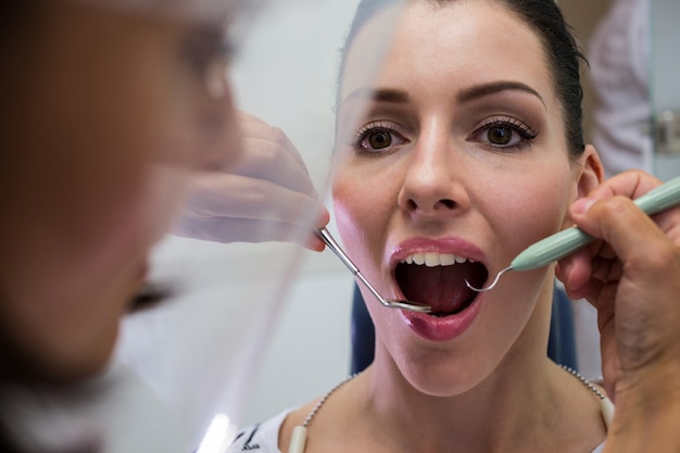 Dentist examining a female patient with tools