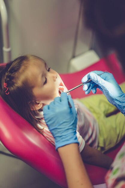 Стоматолог осматривает маленькую девочку в своем кабинете