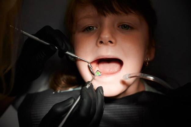 歯科医院で小さな女の子の歯を調べる歯科医