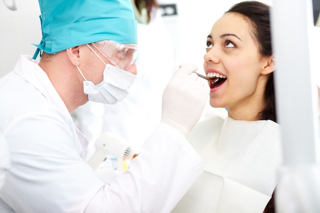 Foto gratuita dentista esaminando denti del paziente