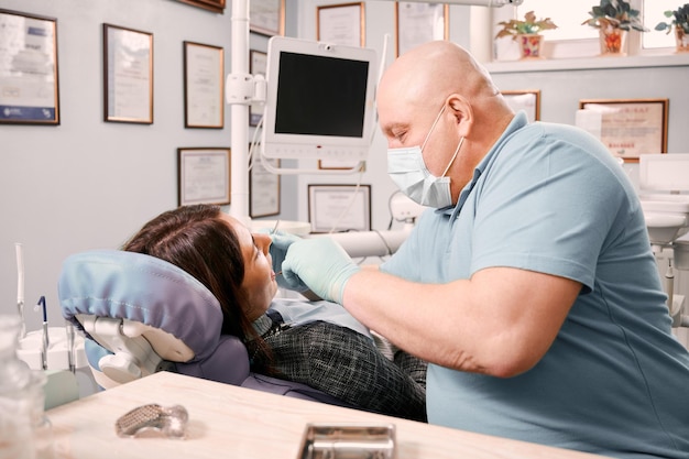 Foto gratuita dentista che esamina i denti del paziente in studio dentistico