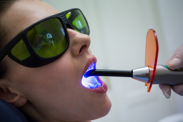 Free photo dentist examining patients teeth with dental curing light