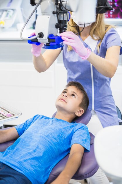 Dentist examining teeth of a boy through microscope