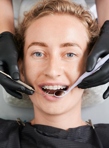 Dentist examining woman teeth with braces