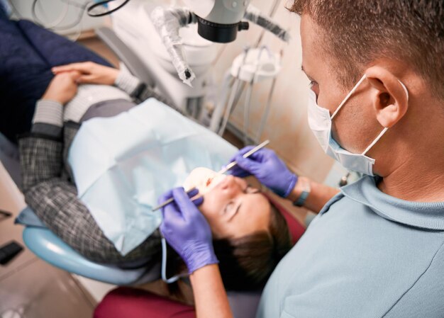 진단 현미경으로 여자 치아를 검사하는 치과 의사