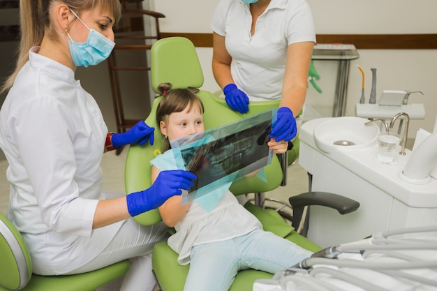 レントゲン写真を見て歯科医と少女の患者