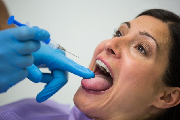 여성 환자에게 주사를주는 치과 의사