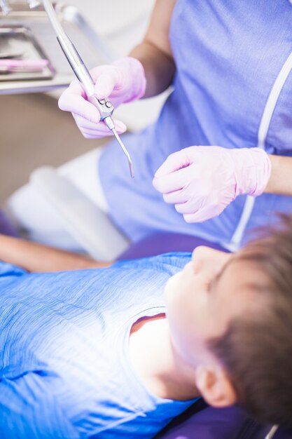 超音波スケーラーを持つ少年の歯を調べる歯科医の手