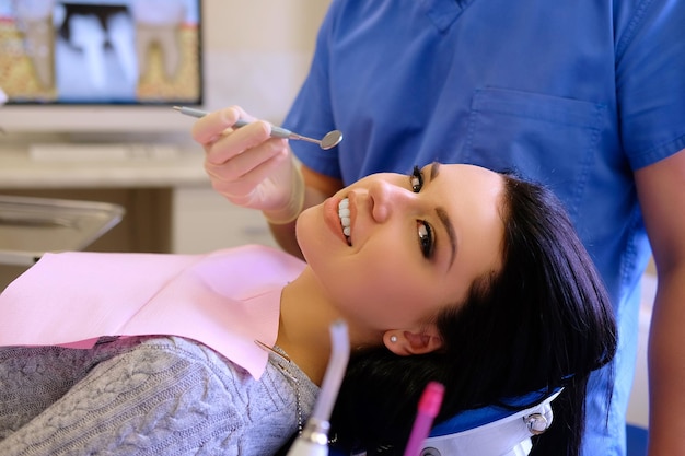 A dentist hands working on young woman patient with dental tools.