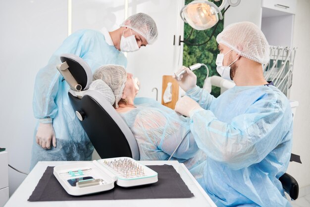 Dentist and his assistant working with a patient in a dentist chair in dentist office