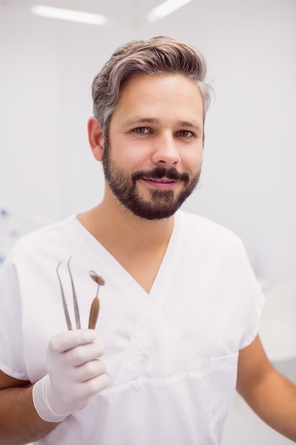 Free photo dentist holding dental tweezers and mouth mirror