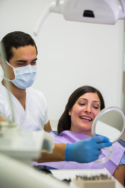 Стоматолог держит зеркало перед пациентом
