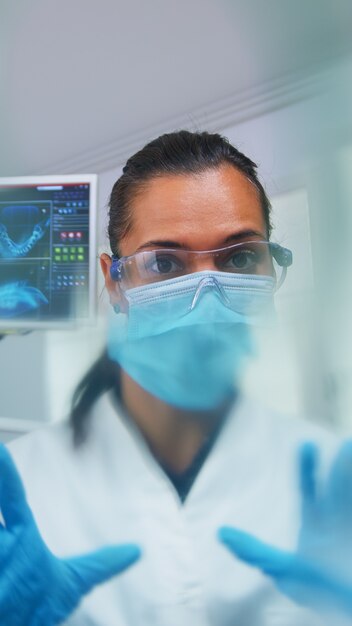 Dentist leaning over patient putting oxigen mask before surgery in stomatological office. Doctor working in modern orthodontic clinic wearing protection mask and gloves during heatlhcare checking