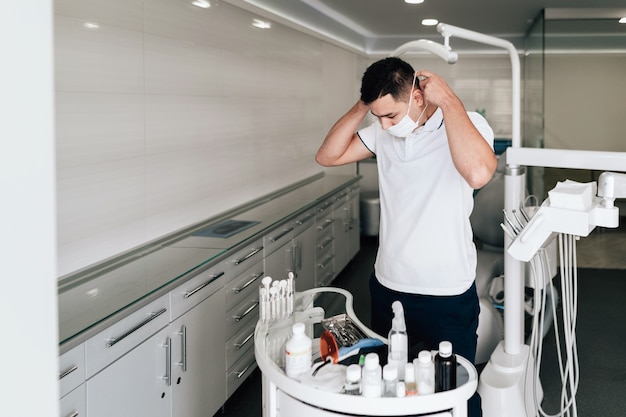 Dentist putting on surgical mask in office