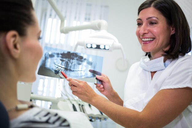 Дантист показывая рентгеновский снимок ее пациенту
