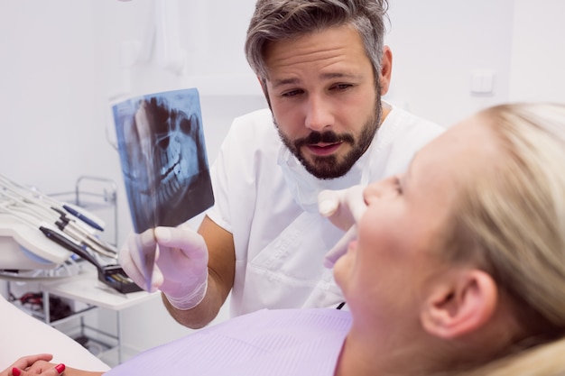 Foto gratuita dentista che mostra i raggi x al paziente