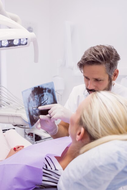 Стоматолог показывает рентгеновский снимок пациенту
