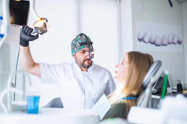 Free photo dentist wearing dental loupe binoculars treating female patient