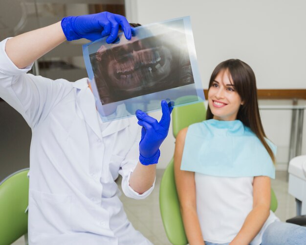 歯科医と女性のレントゲン写真を見る