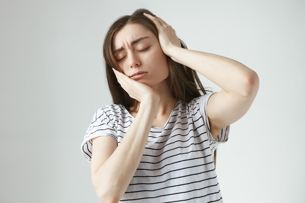 歯科、健康的なライフスタイルと病気の概念。激しい痛みに苦しんでいる、彼女の頬に手をつないで目を閉じて、丸薬が効かない間にひどい歯痛を患っているストレスのたまった若い女性の肖像画