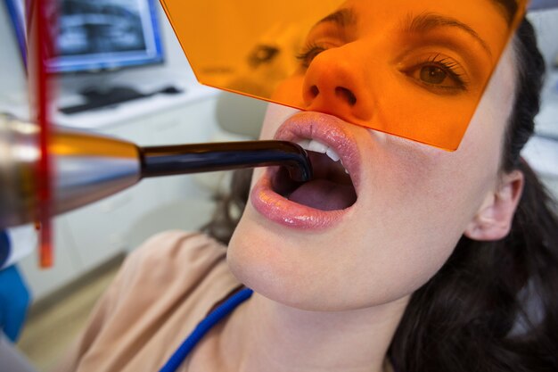 치과 치료 빛으로 여성 환자를 검사하는 치과 의사 프리미엄 사진