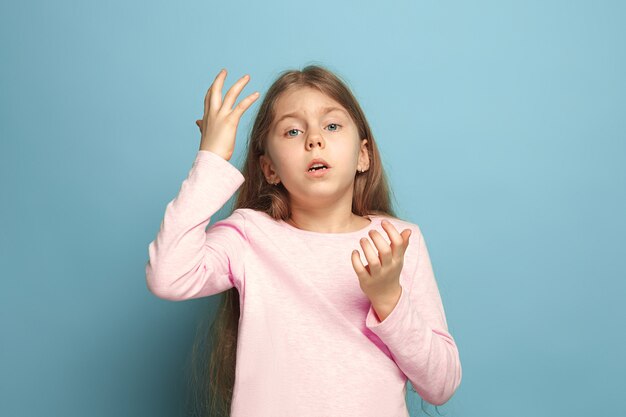 The deplorable girl. The sad teen girl on a blue studio background. Facial expressions and people emotions concept. Trendy colors. Front view. Half-length portrait