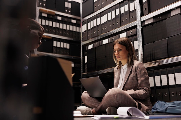 Depository workers discovering bookkeeping record in storage room, discussing administrative report. Diverse businesspeople analyzing management files, checking accountancy documents