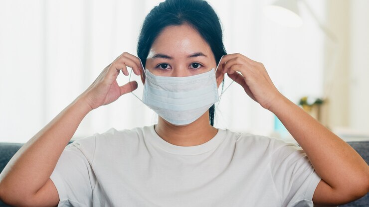 無料Photo 落ち込んでいるアジアビジネスの女性の社会的距離が家にいるとき、家のリビングルームのソファーに座っている防護マスクと自己検疫時間、中国でのパンデミック、コロナウイルスの概念。