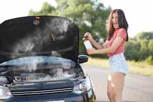 Foto gratuita l'autista femminile bruna depressa si trova vicino all'auto rotta con il cofano aperto, cerca di risolvere da sola il problema tecnico mentre aspetta il tecnico dell'auto, apre la bocca ampiamente, esclama con grande disperazione