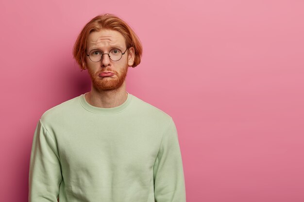 Depressed dissatisfied man has gloomy sullen look, purses lower lip