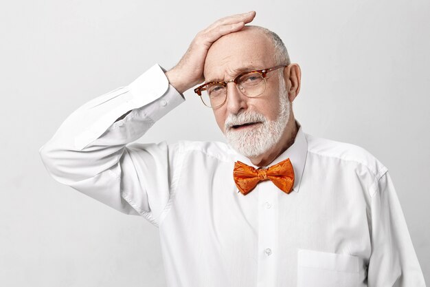 Depressed elderly 65 year old businessman with thick gray beard having frustrated unhappy painful facial expression